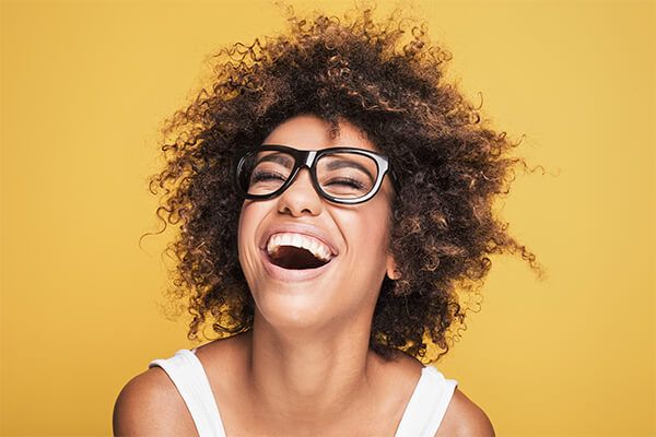 Lachende erwachsene Frau nach Behandlung mit unsichtbarer Zahnspange